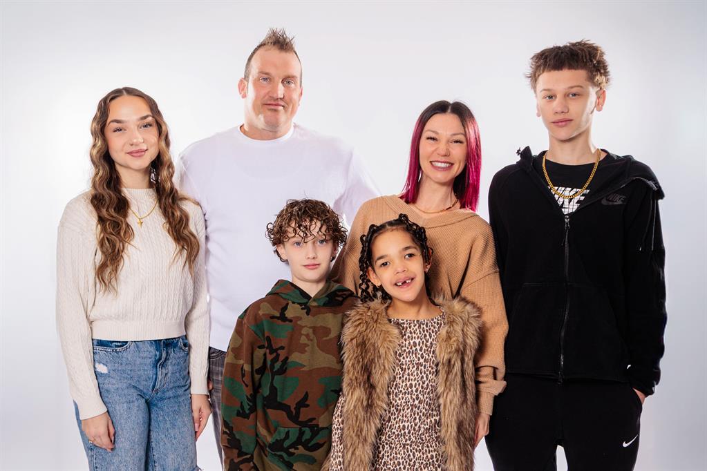 Family of six poses for picture in front of white backdrop